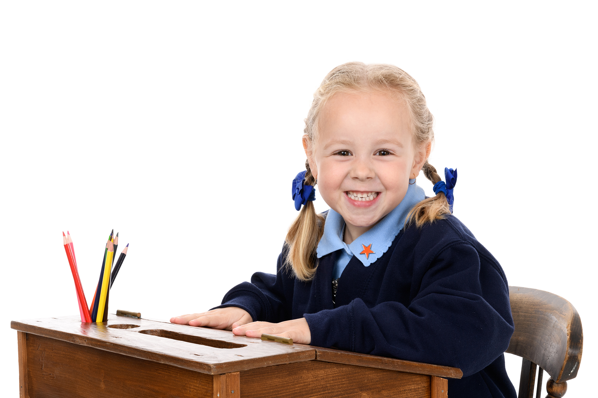 primary school girl in school uniform sitting at a desk for her school photographs, by photographer in Hampshire